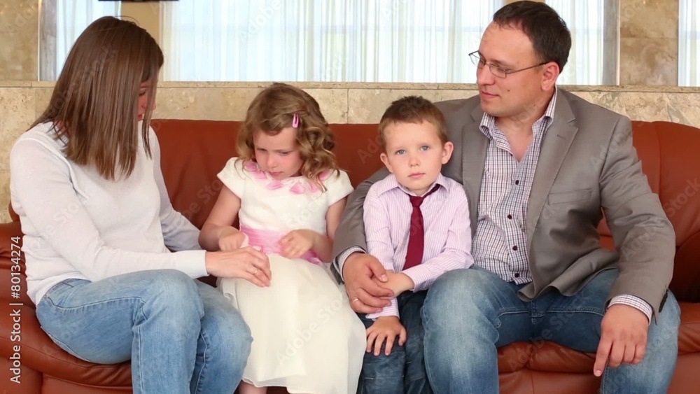 Parents with their son and daughter are sitting on the couch Parents with their son and daughter are sitting on the couch