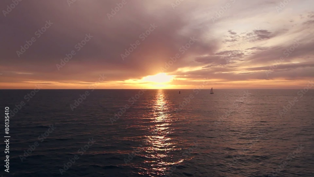 Sunset over the Pacific Ocean with a small sail boat turning on the sea. Sunset over the Pacific Ocean with a small sail boat turning on the sea.