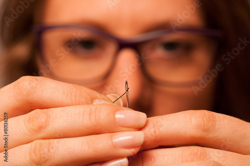 Woman putting string through needle