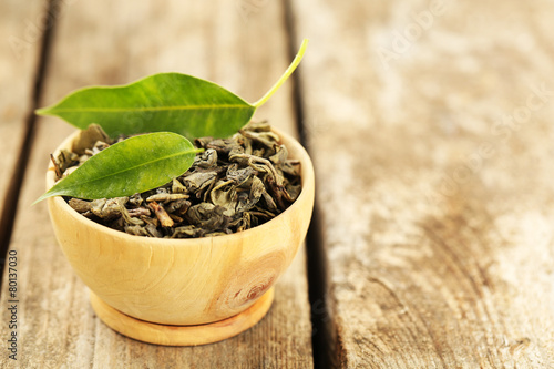 Green tea with leaf in bowl on old wooden table