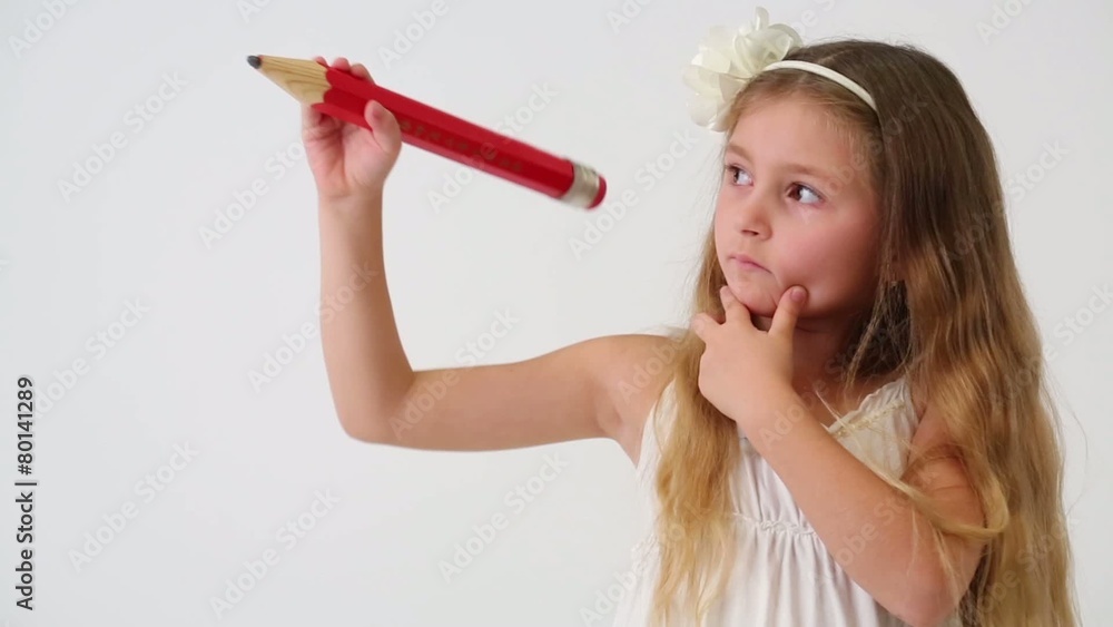 Cute little girl with thoughtful face drawing air big red pencil Cute little girl with thoughtful face drawing air big red pencil