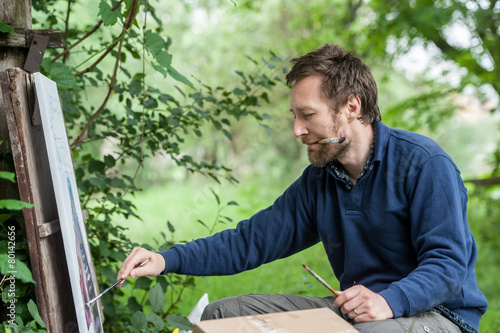 Fotografie Male artist on painting on canvas in outdoor.