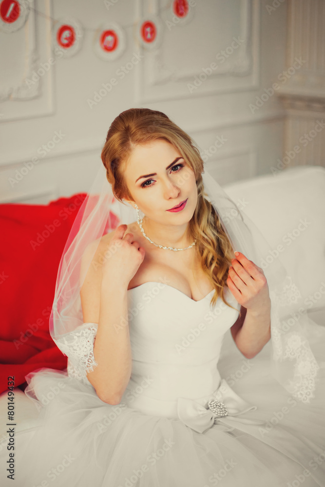 Blonde pretty bride on sofa with red wrap. Soft, vanilla color Blonde pretty bride on sofa with red wrap. Soft, vanilla color