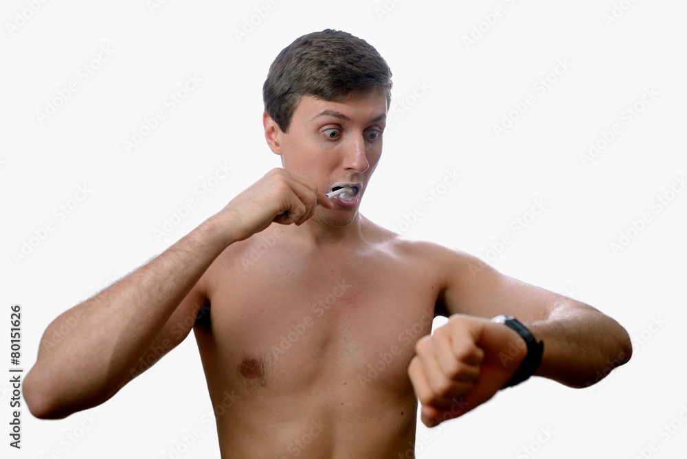 Fototapeta premium Man brushing teeth also looks on at watch on white background