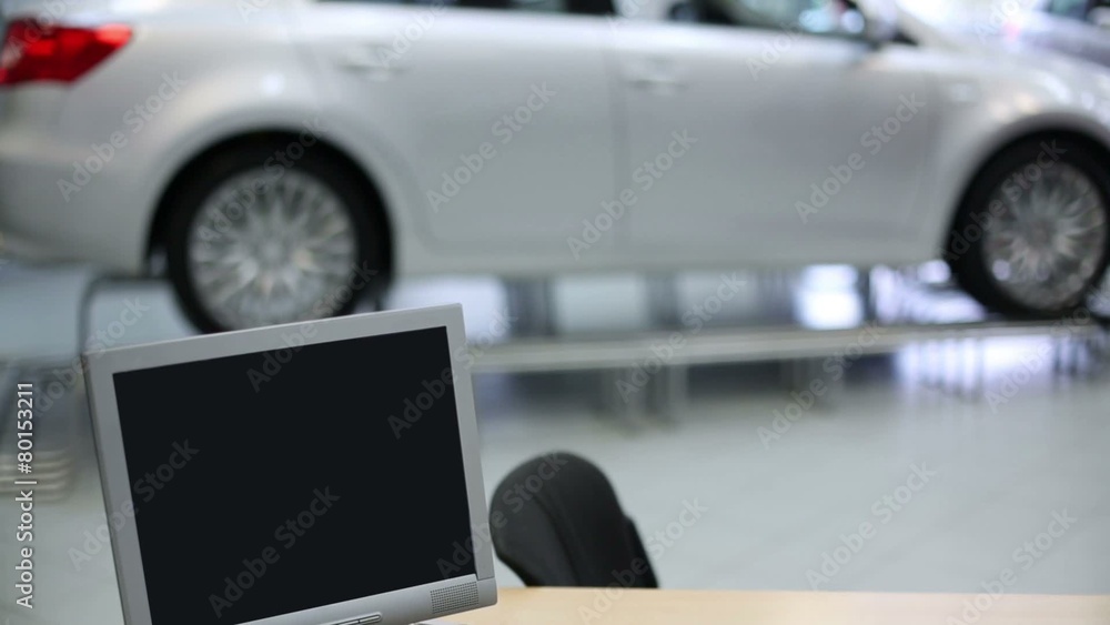 Computer with documents on wooden table and new cars Computer with documents on wooden table and new cars