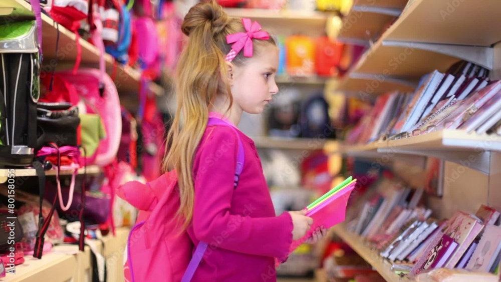 Little girl chooses the exercise-book in the department store Little girl chooses the exercise-book in the department store