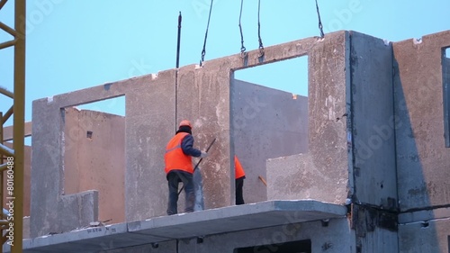 Workers mount concrete slab to proper place at building under construction. photo