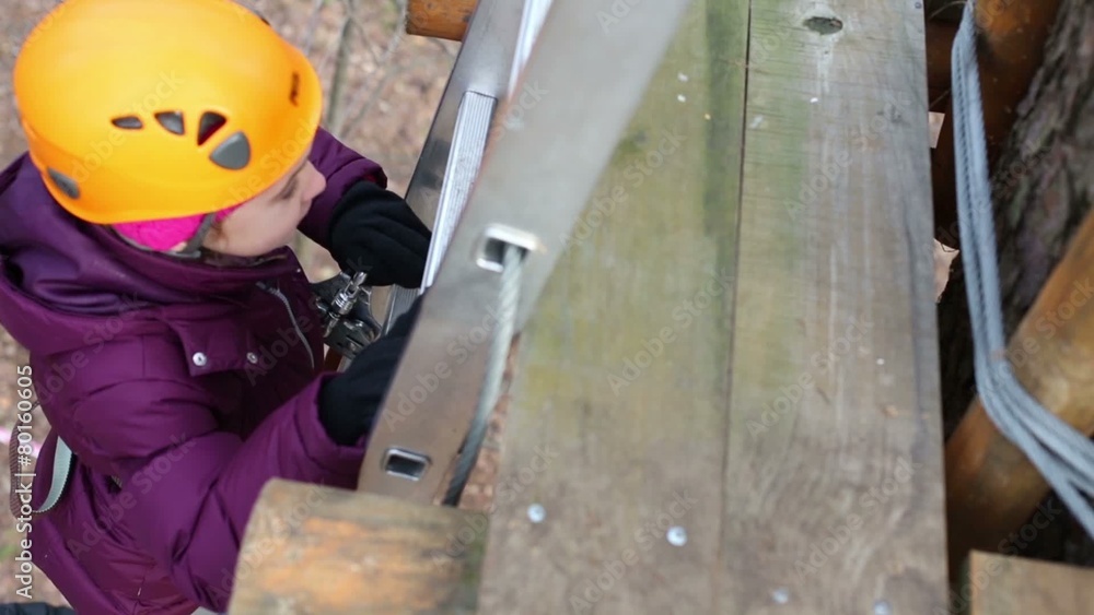 Girl in orange helmet climbs up ladder outdoor on autumn day Girl in orange helmet climbs up ladder outdoor on autumn day