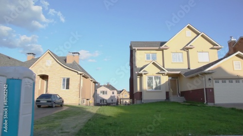 Many cottages in village under blue sky with clouds at sunny summer day, carview in motion photo