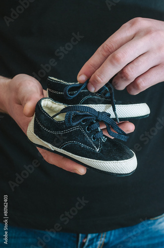 Baby shoes on parental hand