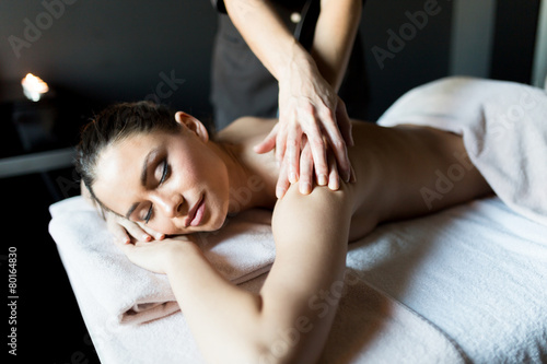 Beautiful, young lady having her shoulder and body massaged