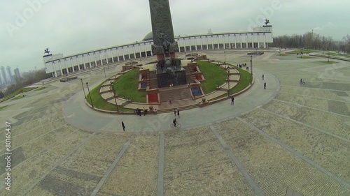 Tourists walk near Monument with St. George piercing serpent