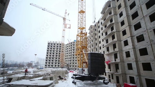 Cranes work at construction site, moving various freights.  photo