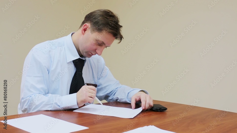 Man sitting at a table and reads document that is going to sign Man sitting at a table and reads document that is going to sign