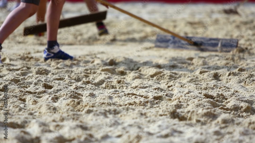 People flatten sand surface at beach volleyball pitch by tools People flatten sand surface at beach volleyball pitch by tools