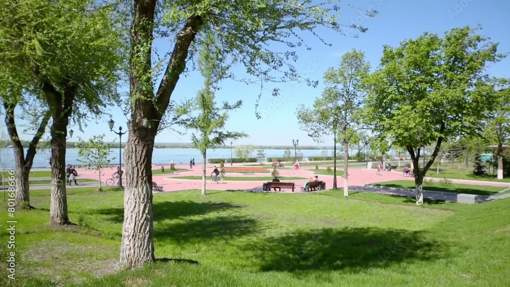 People sit on benches and walk by park on quay of Volga river People sit on benches and walk by park on quay of Volga river