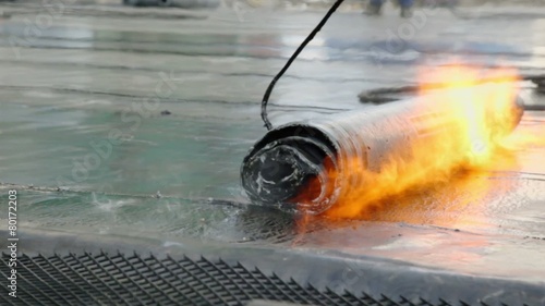 Worker uses hook to roll up ruberoid for waterproofing photo