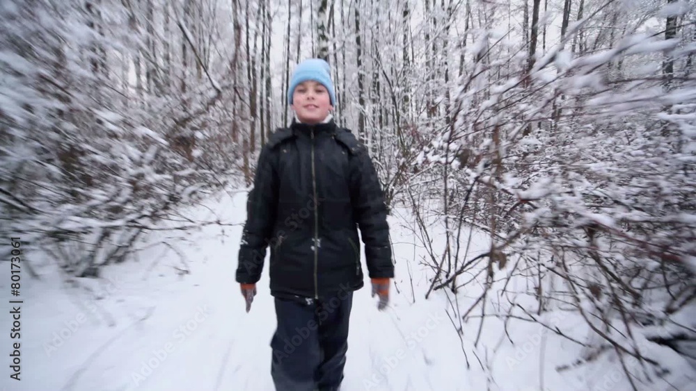 Young boy in warm clothes walks by park at winter day Young boy in warm clothes walks by park at winter day