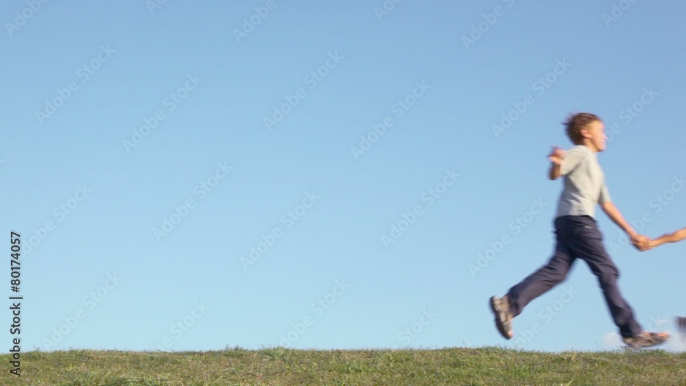 Children boy with little girl hold hands and run by grass hill, slow motion Children boy with little girl hold hands and run by grass hill, slow motion