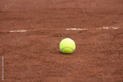 One green tennis ball on the clay court