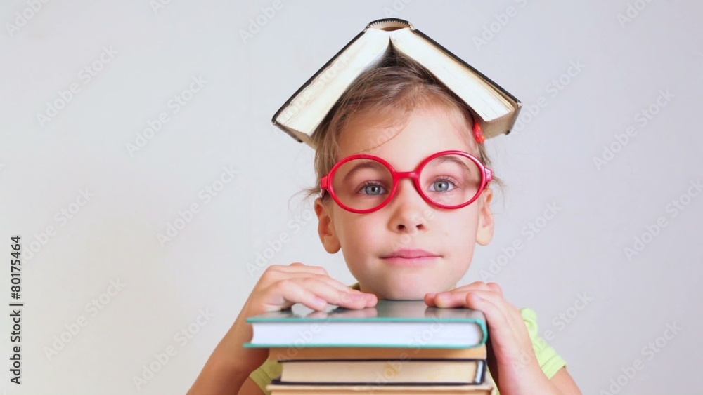 little girl with book on head lies smiling the pile of books little girl with book on head lies smiling the pile of books