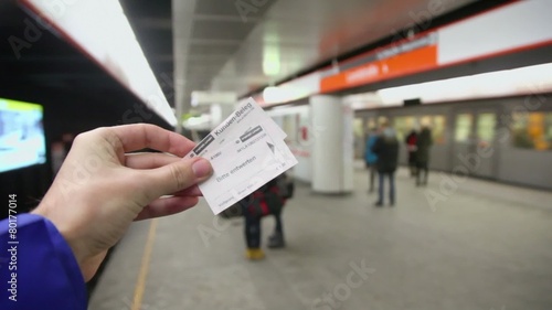 Hand hold two tickets at metro station with passengers and train photo