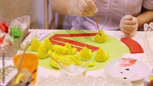 gloved hands creating of color sweet figures in confectionary photo