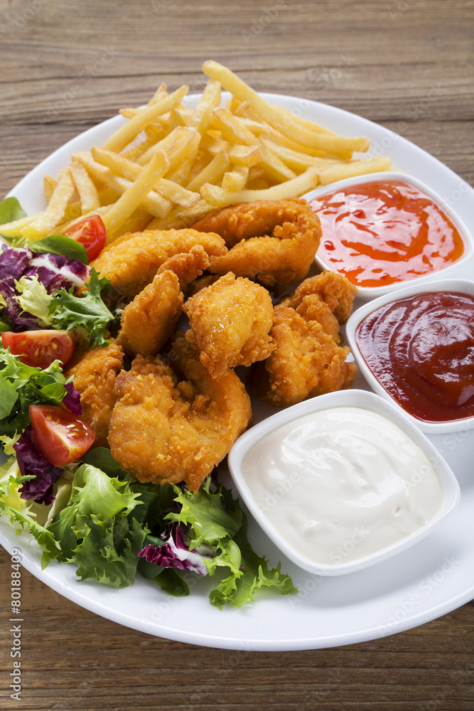 Nuggets and chips on a plate served with dip and salads Nuggets and chips on a plate served with dip and salads