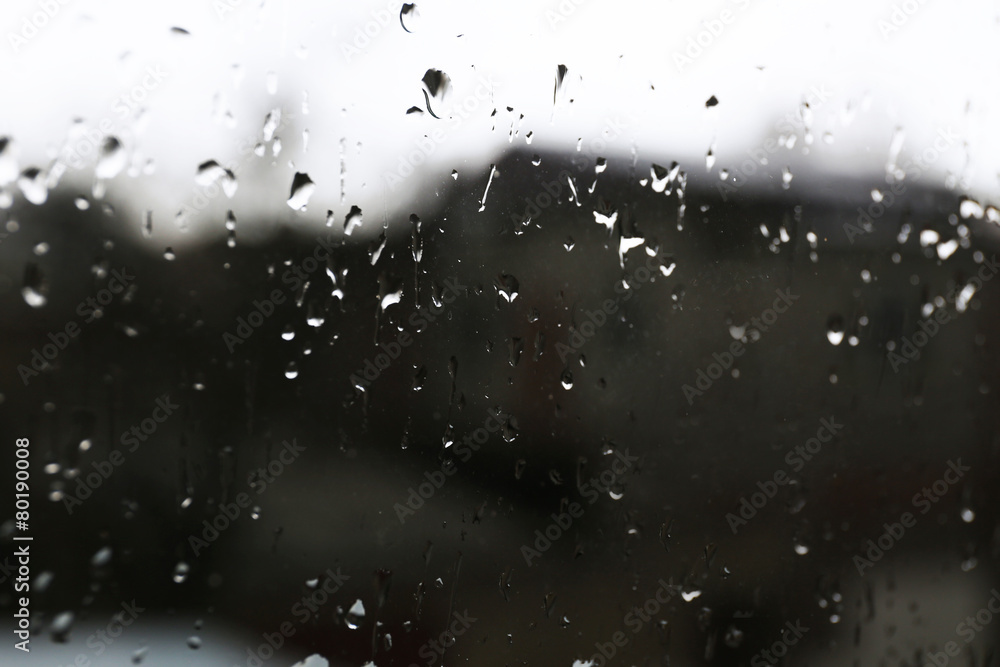 Raindrops on glass window overlooking the street on background Raindrops on glass window overlooking the street on background