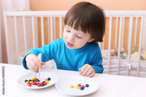 Happy little boy plays with pincers and beads. Educational playi