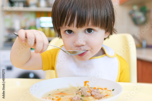 Close up of lovely little boy eating soup photo