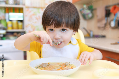 2 years boy eating soup with meat balls at home kitchen