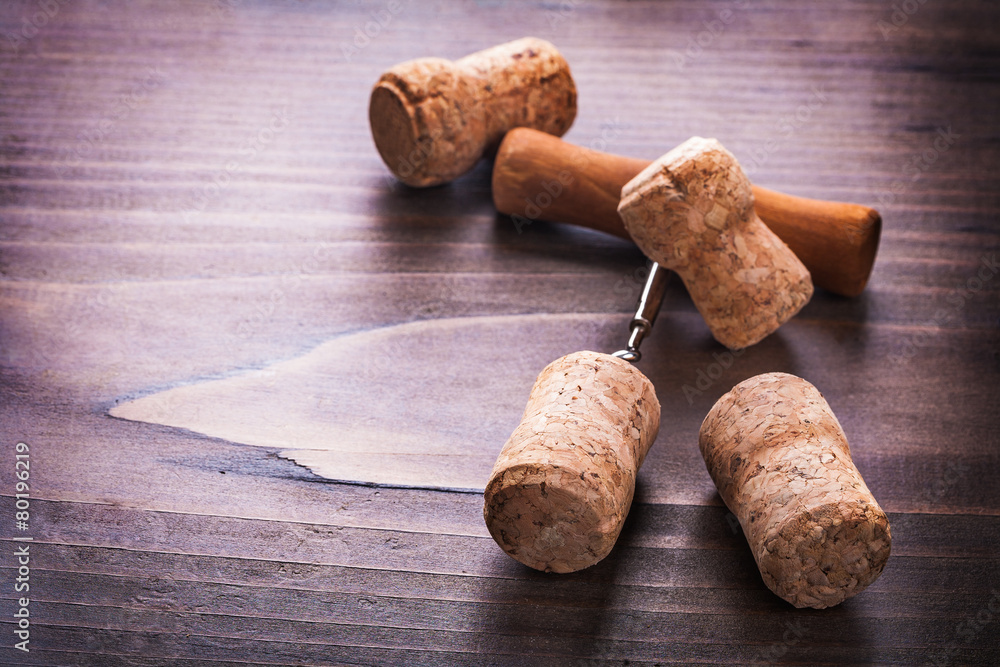 four corks and corkscrew on vintage wooden board alcohol concept