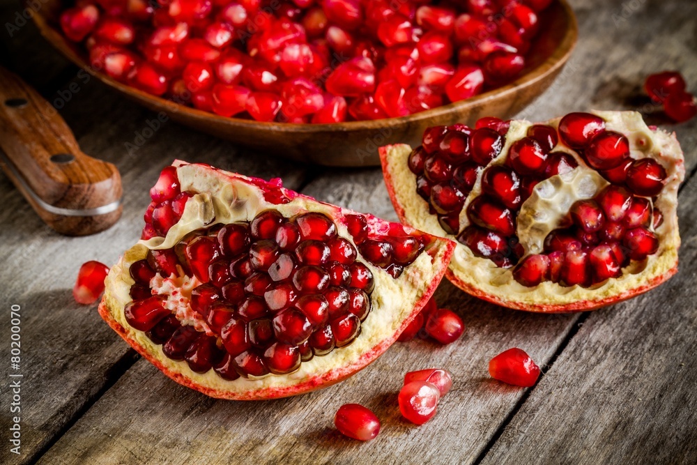 Ruby pomegranate open with seeds closeup on wooden table Ruby pomegranate open with seeds closeup on wooden table