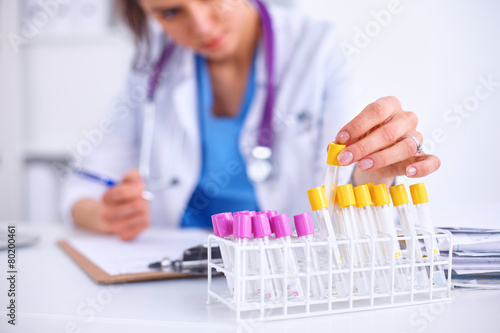 Woman researcher is surrounded by medical vials and flasks