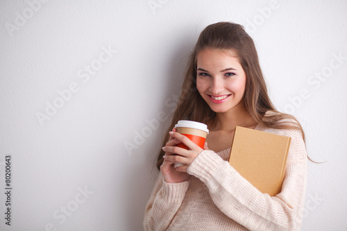 Portrait  a young woman with cup of tea or coffee, holding book