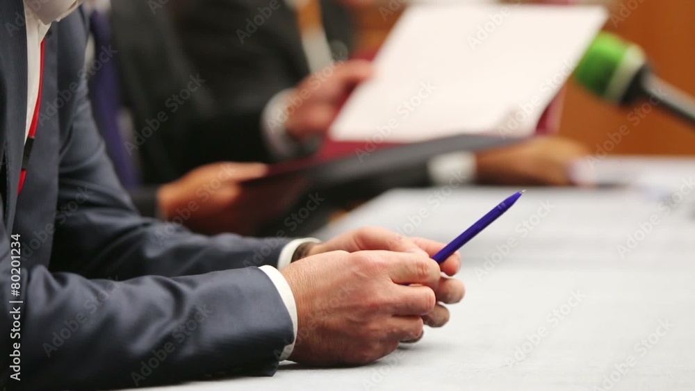 Male hands in suit at table hold pen at business meeting Male hands in suit at table hold pen at business meeting