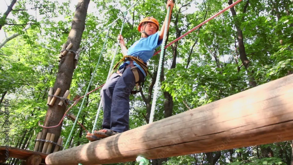 boy in helmet walks by pendant tree log in rope park boy in helmet walks by pendant tree log in rope park