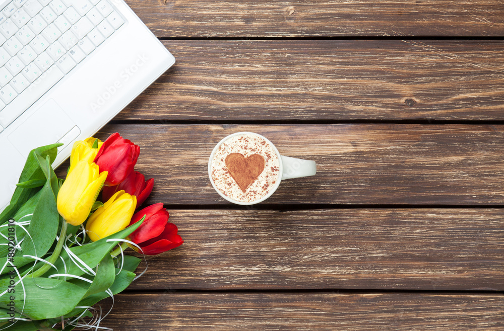 Cup of cappuccino with heart shape and computer Cup of cappuccino with heart shape and computer