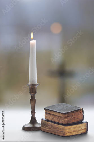 Old two prayer  books and burning candle with a candlestick