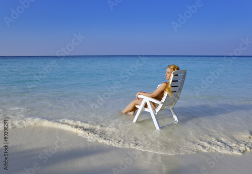 Young pretty woman in a beach chair in sea photo