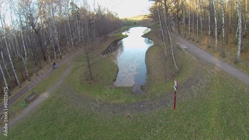 People walk by path near Putyaevskiy pond in park at autumn day photo