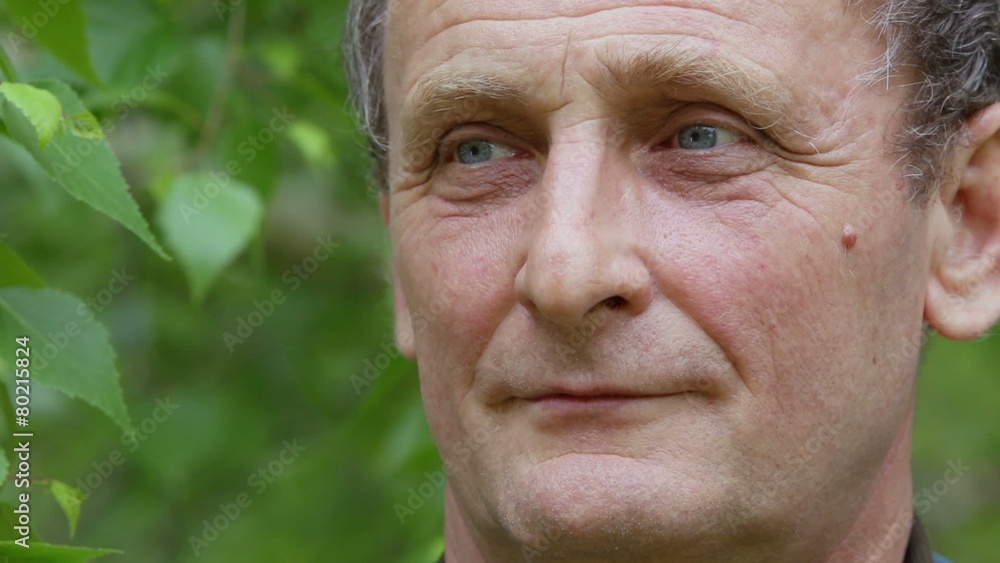 Elderly man looks and turns head near foliage of tree Elderly man looks and turns head near foliage of tree