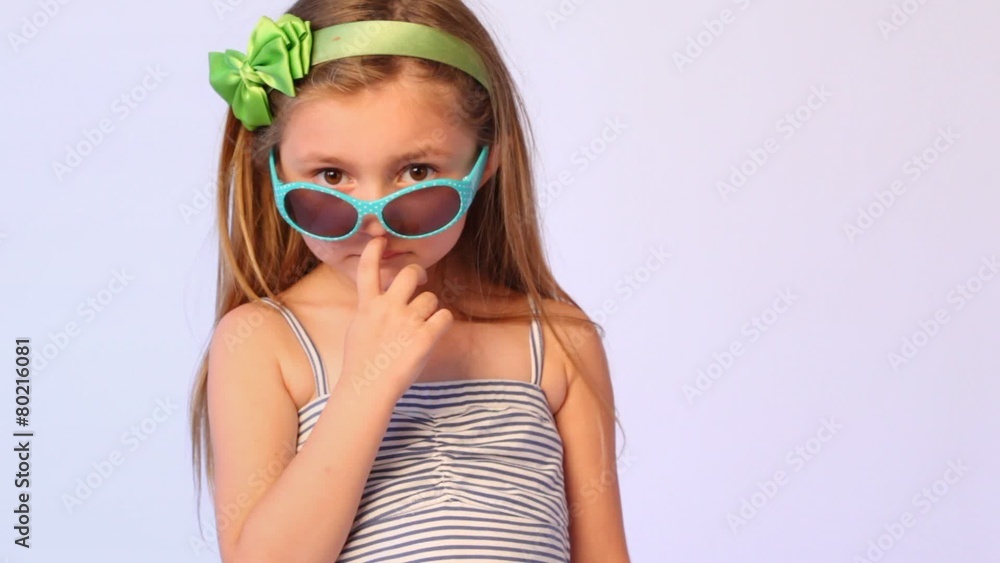girl wearing spectacles on nose pulls them finger over eyes and sticks out lips girl wearing spectacles on nose pulls them finger over eyes and sticks out lips