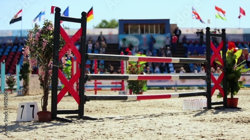 People sit on tribune near arena with striped barrier