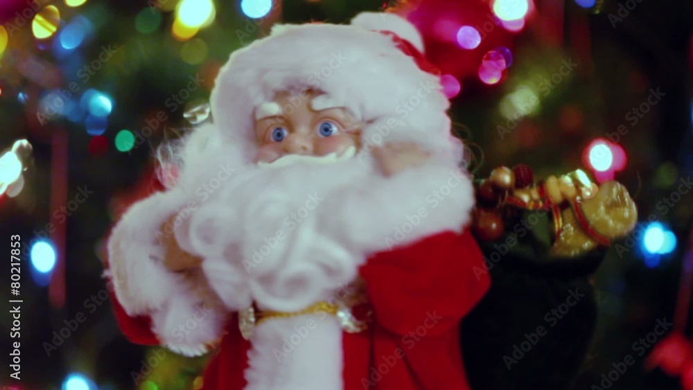 Santa Claus toy dances near Christmas tree with garland Santa Claus toy dances near Christmas tree with garland