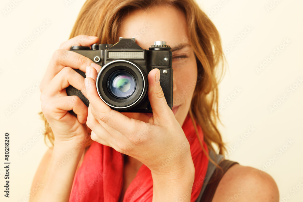 Young redhead woman looking through viewfinder with an old 35mm Young redhead woman looking through viewfinder with an old 35mm