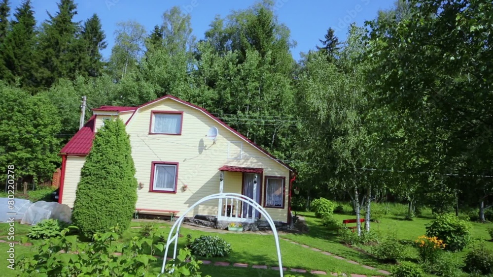 Modern country house with green lawn among plants at summer day Modern country house with green lawn among plants at summer day