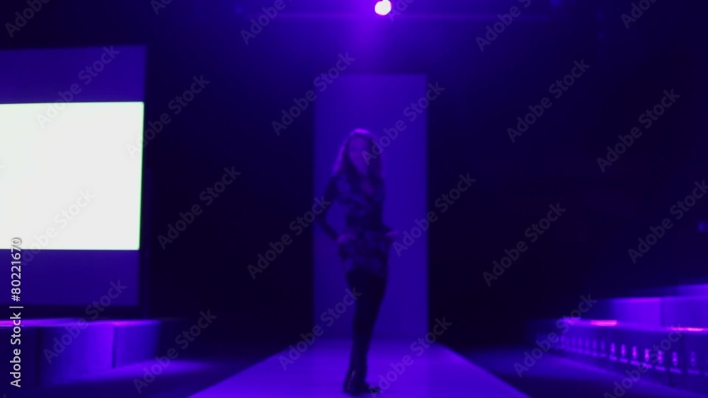 Beautiful girl with curly hair walks and poses on podium in dark Beautiful girl with curly hair walks and poses on podium in dark