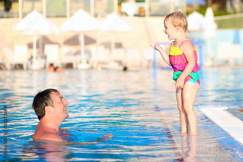 Father and daughter having fun in swimming poo